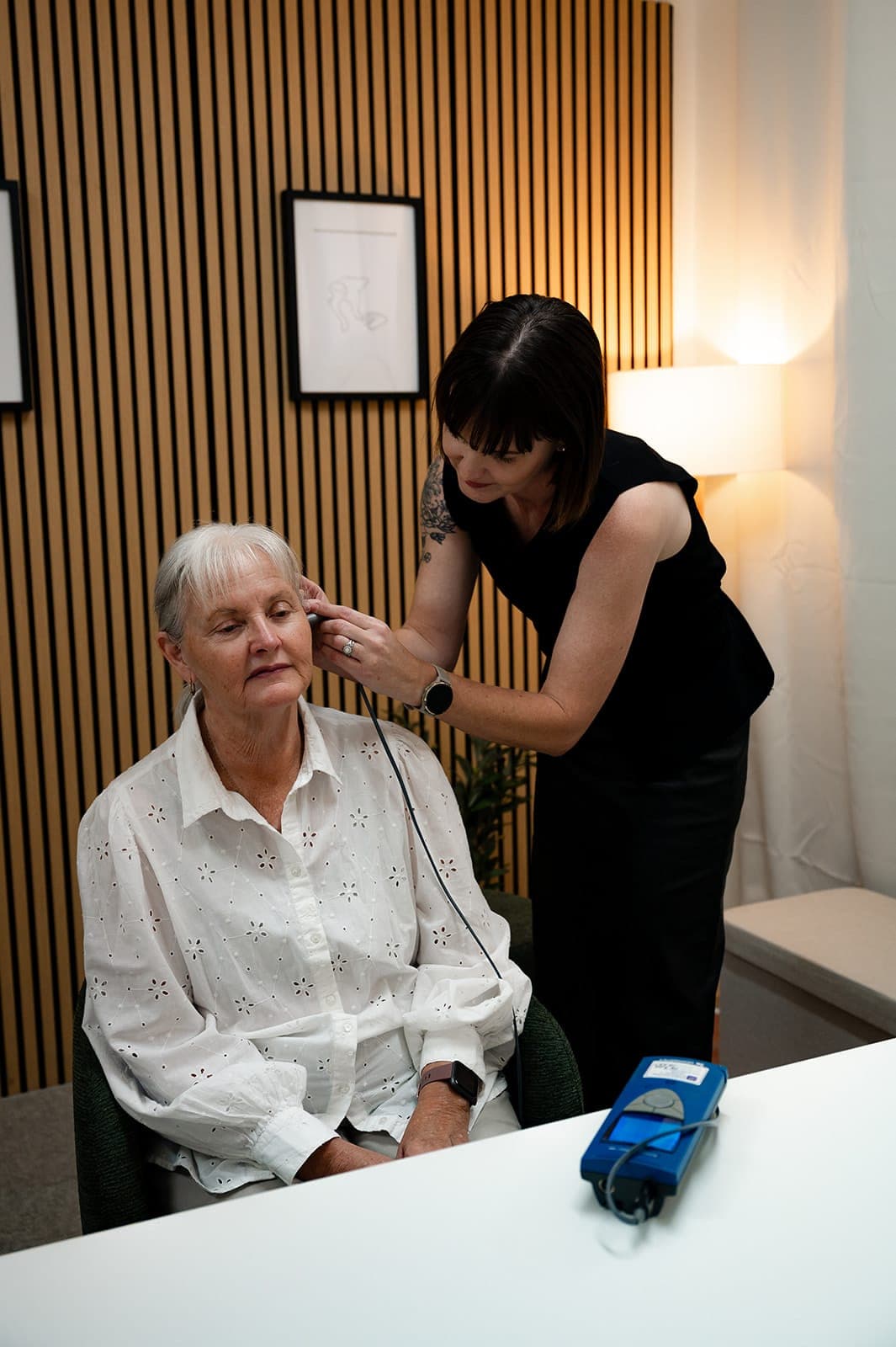 Dr Alison Collins placing a tympanometry probe in an older woman's ear