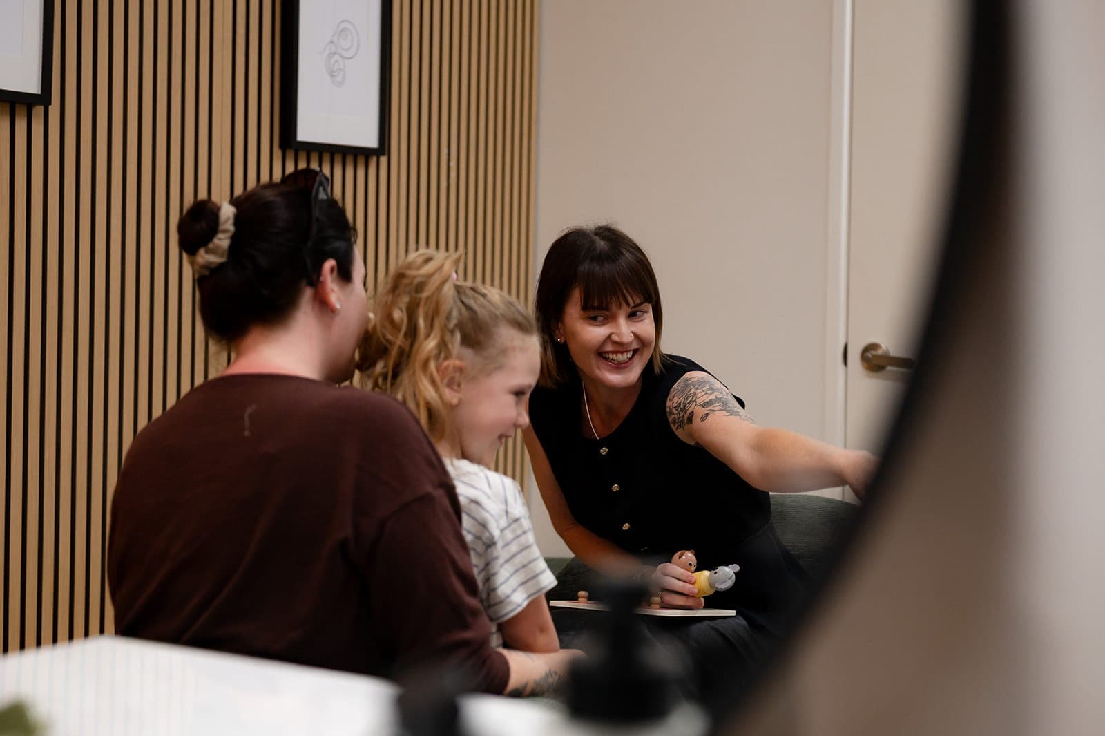 Dr Alison Collins interacting with a child and her parent during a hearing assessment