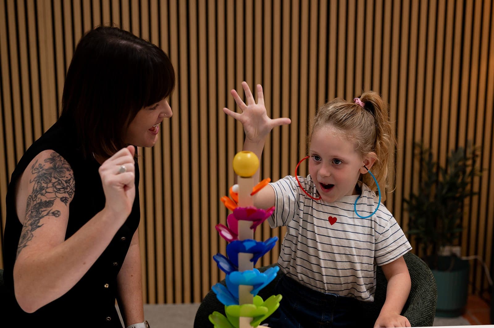 A child taking part in a play-based hearing activity with Dr Alison Collins while her parent watches